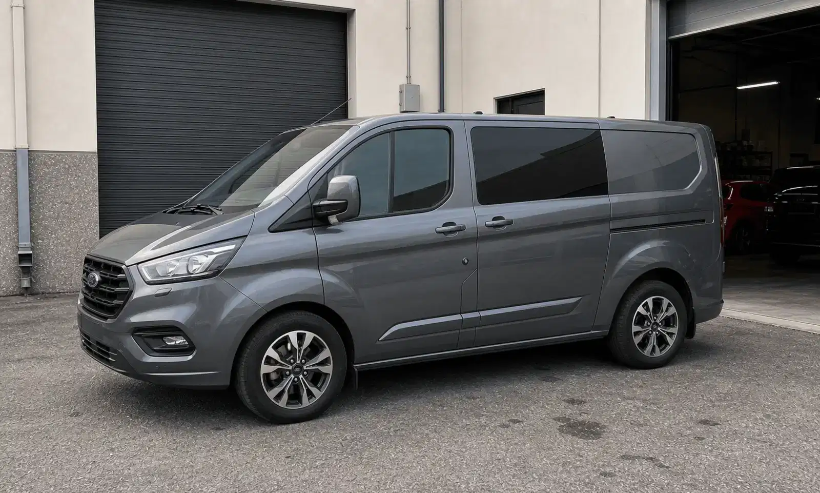 Grey Ford Transit Custom with light tint outside a tint workshop