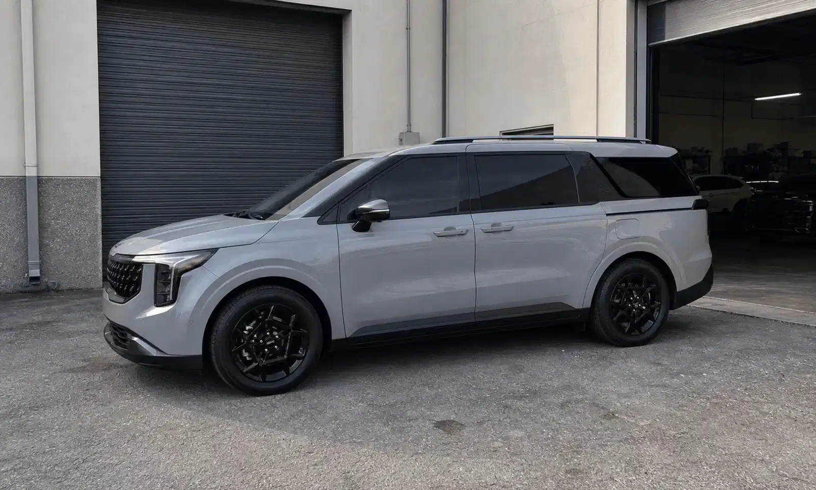 Nardo grey Kia Carnival with freshly tinted windows outside a tint workshop
