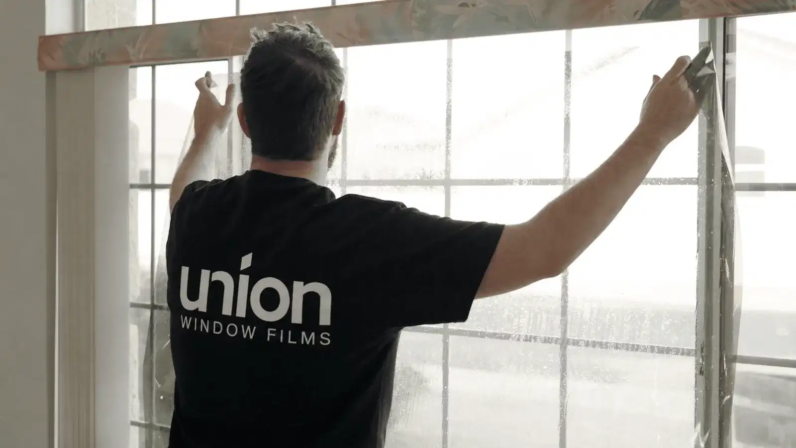 Union installer preparing architectural window film on residential glass